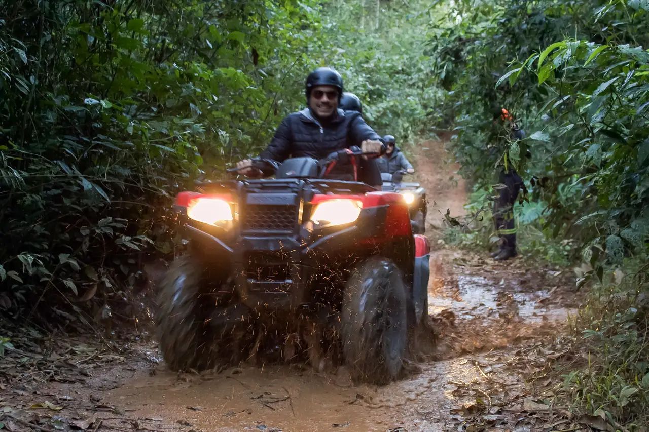 Piloto em quadriciclo na lama com farol aceso