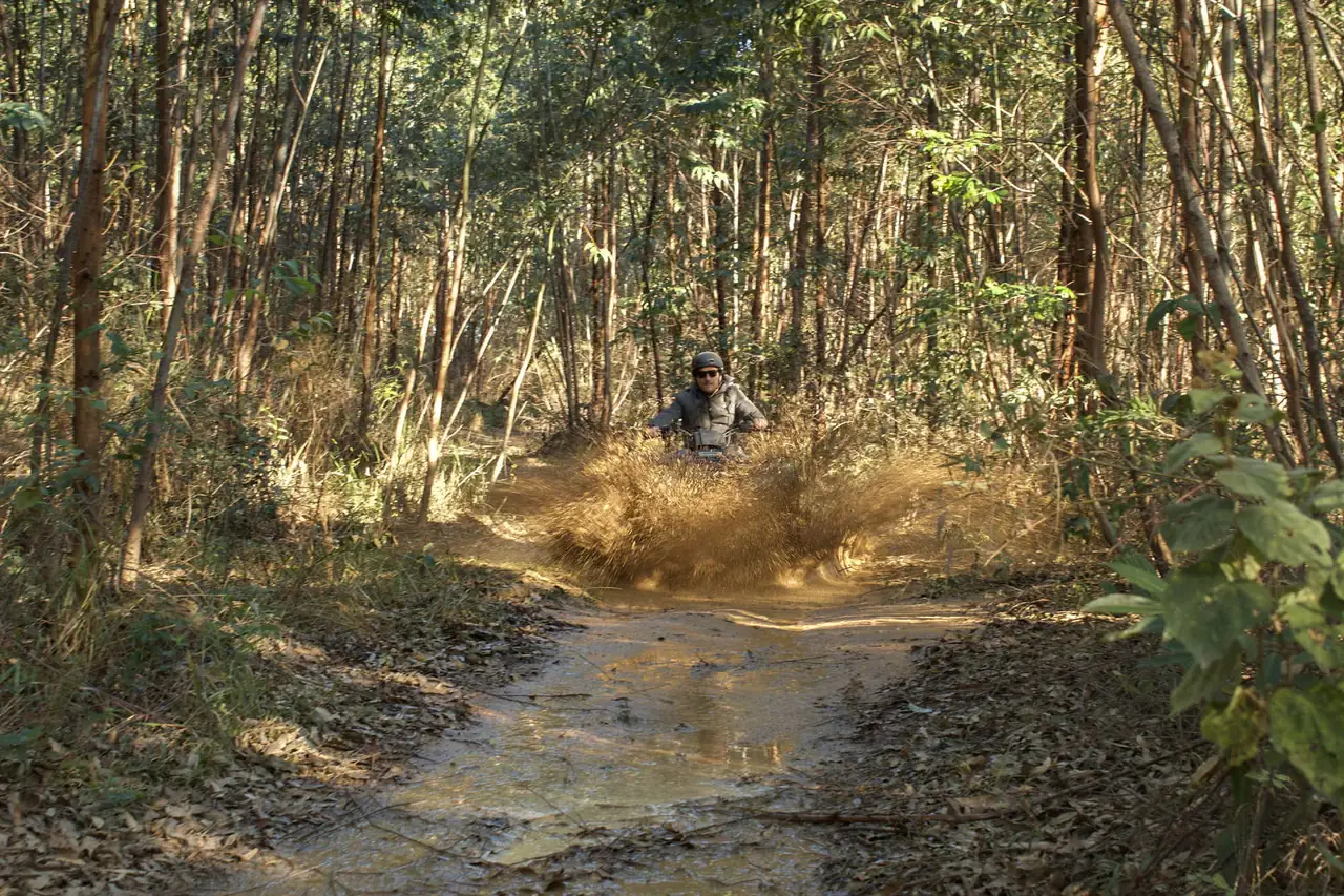 Quadriciclo atravessando lama em trilha na floresta